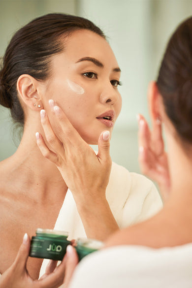 Model with QUL Beauty Night Repair Moisturizer with moisturizer on her cheek
